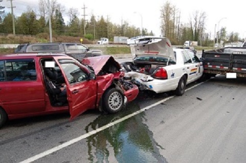 damaged red car which rear ended an RCMP police cruiser on the side of the road