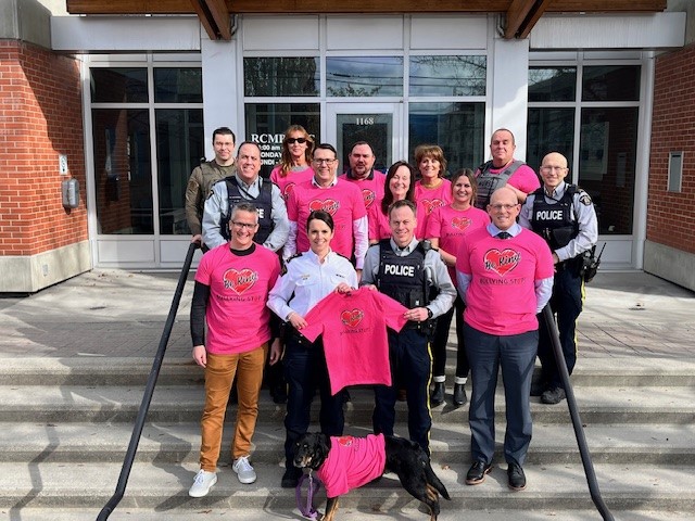 Group of people standing on a set of stairs, wearing pink shirts in support of Pink Shirt Day